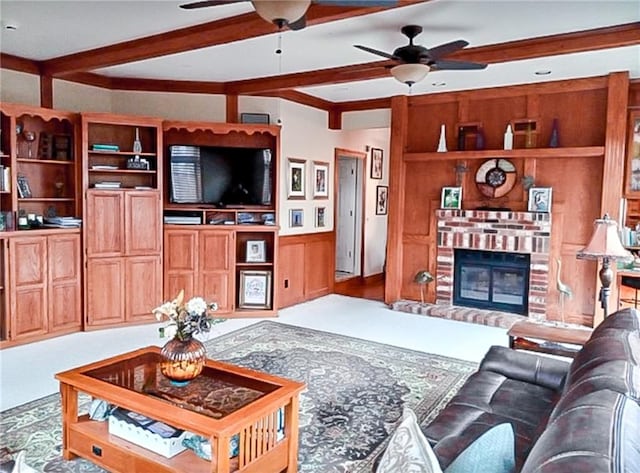 living room with ceiling fan, built in shelves, beam ceiling, and a brick fireplace