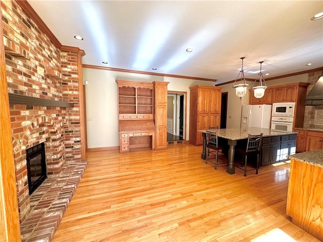 dining area with brick wall, ornamental molding, light wood-type flooring, and a fireplace