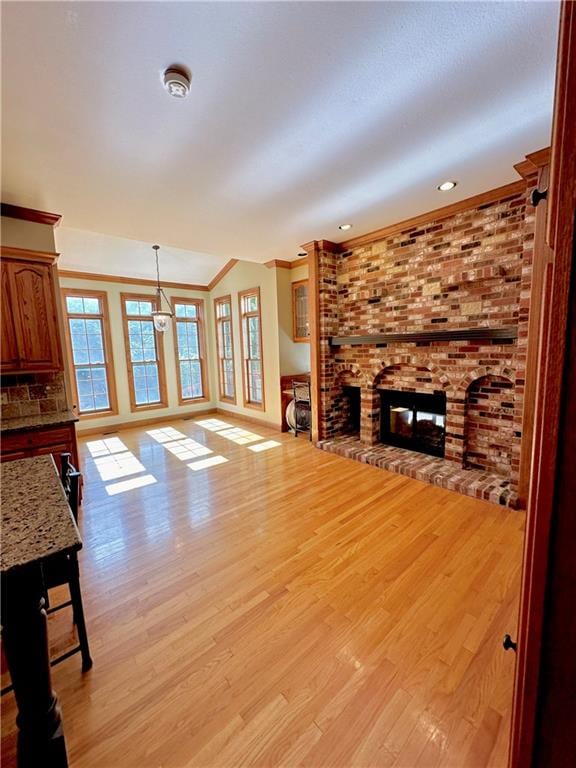 unfurnished living room with light hardwood / wood-style flooring, a fireplace, and brick wall