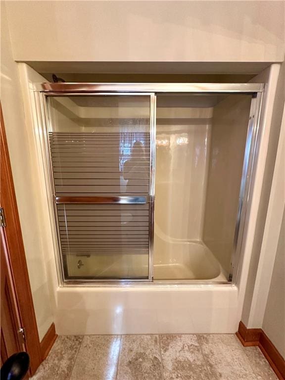 bathroom with tile floors and bath / shower combo with glass door