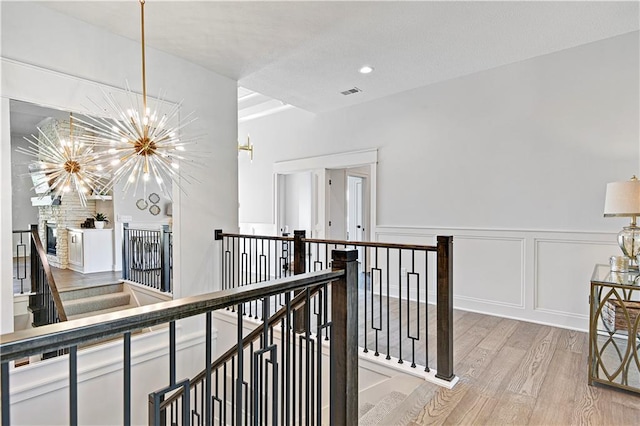 24932 W 98th Pl, Lenexa, KS 66227 - corridor with an upstairs landing, light wood-style floors, a chandelier, a decorative wall, and a wainscoted wall