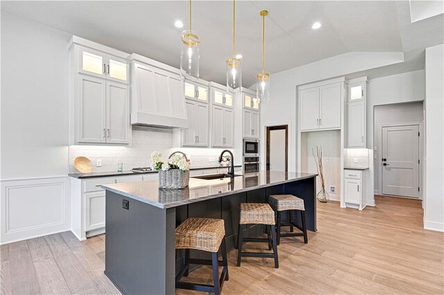 24932 W 98th Pl, Lenexa, KS 66227 - kitchen with a sink, stainless steel appliances, light wood finished floors, backsplash, and a kitchen island with sink