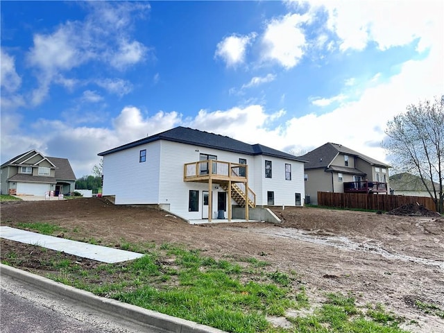 rear view of house with a wooden deck, fence, a residential view, and stairs