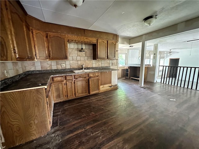 321 Pecan St, Chetopa, KS 67336 - kitchen featuring a sink, dark wood-type flooring, brown cabinets, dark countertops, and backsplash