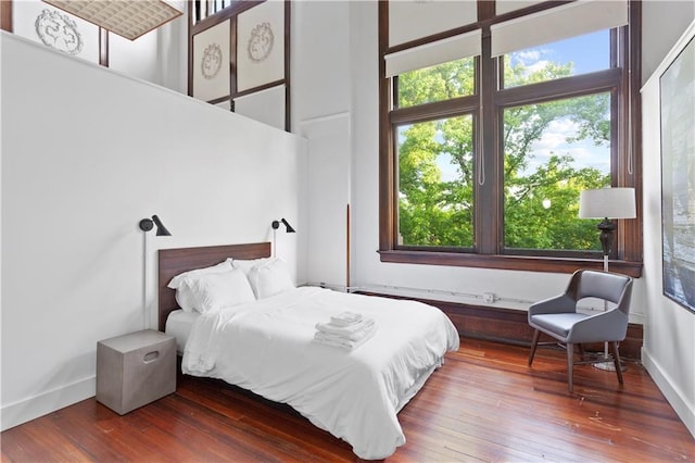 bedroom with a towering ceiling and wood-type flooring