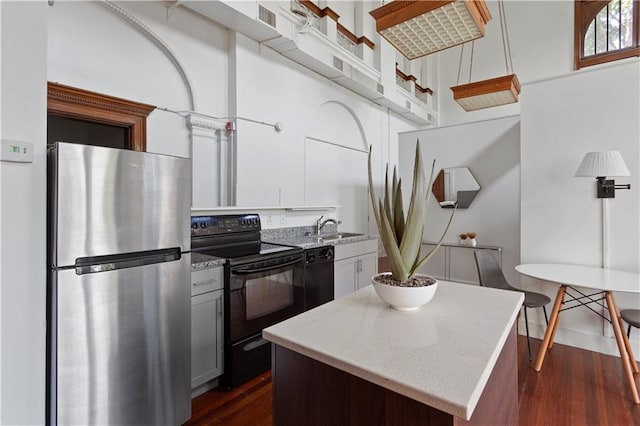 kitchen with sink, dark wood-type flooring, black appliances, and a center island