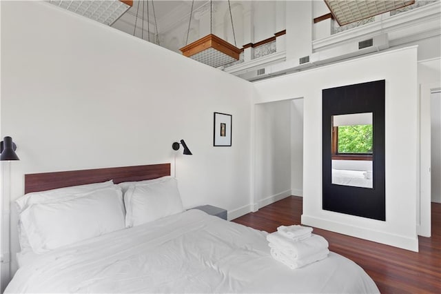 bedroom with a towering ceiling and dark hardwood / wood-style floors