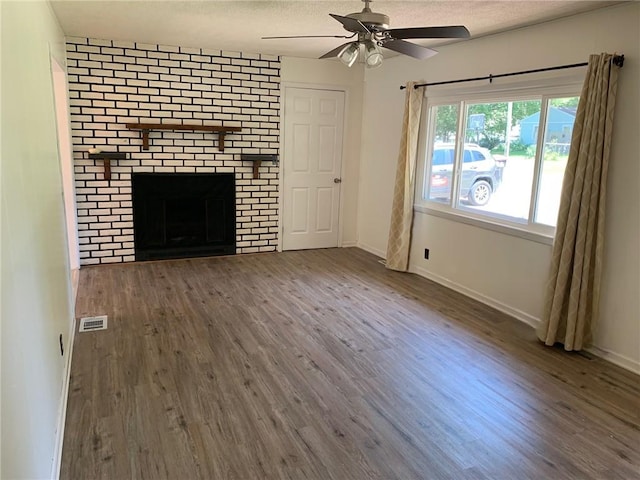 unfurnished living room featuring a brick fireplace, ceiling fan, and dark wood-type flooring