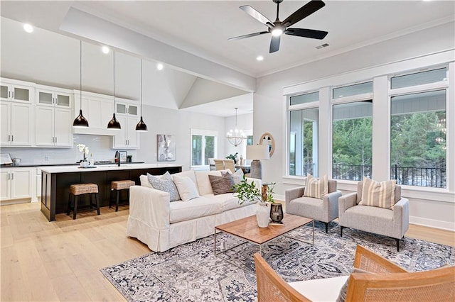 living room featuring ceiling fan with notable chandelier, vaulted ceiling, ornamental molding, and light hardwood / wood-style flooring