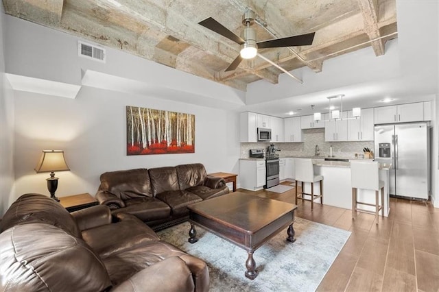 living room with sink, ceiling fan, and light wood-type flooring