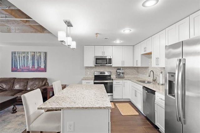 2980 Baltimore Ave Unit 2204, Kansas City, MO 64108 - kitchen featuring appliances with stainless steel finishes, a center island, a sink, decorative backsplash, and white cabinets