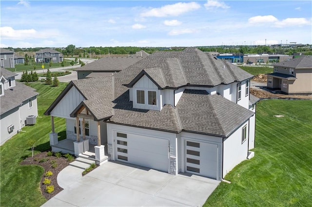 view of front of property featuring a garage, concrete driveway, a shingled roof, and a front yard