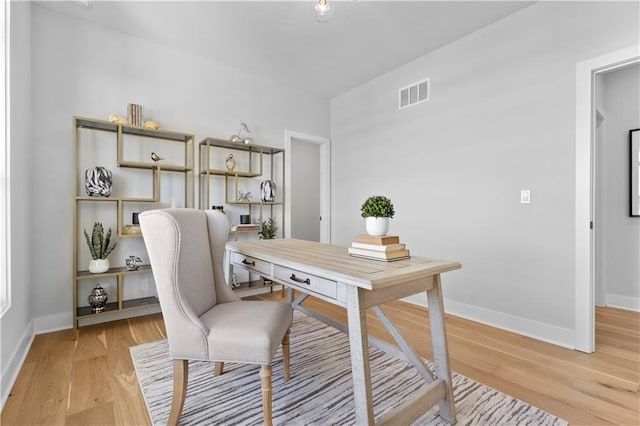 office space featuring baseboards, visible vents, and light wood finished floors