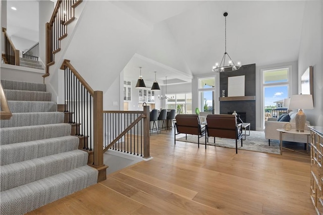 interior space featuring high vaulted ceiling, a large fireplace, a notable chandelier, and wood finished floors