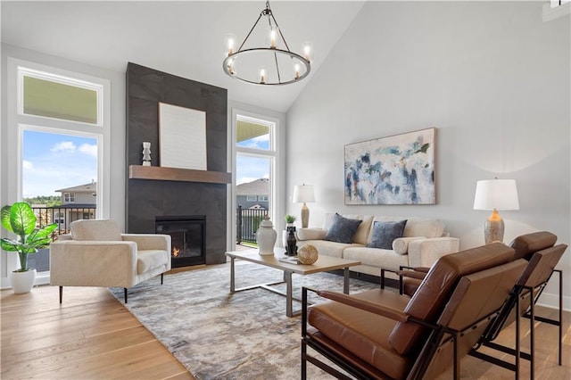 living room featuring a large fireplace, high vaulted ceiling, wood finished floors, and an inviting chandelier