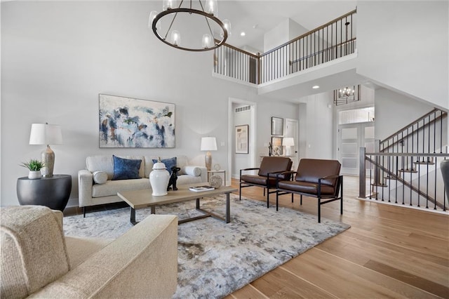 living room featuring an inviting chandelier, stairs, baseboards, and wood finished floors