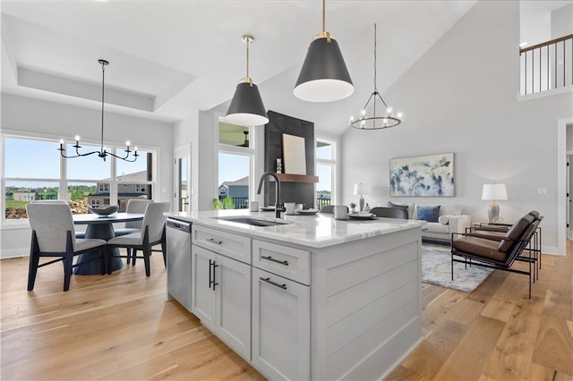 kitchen with dishwasher, a chandelier, a raised ceiling, and a sink