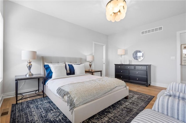 bedroom with visible vents, baseboards, and wood finished floors