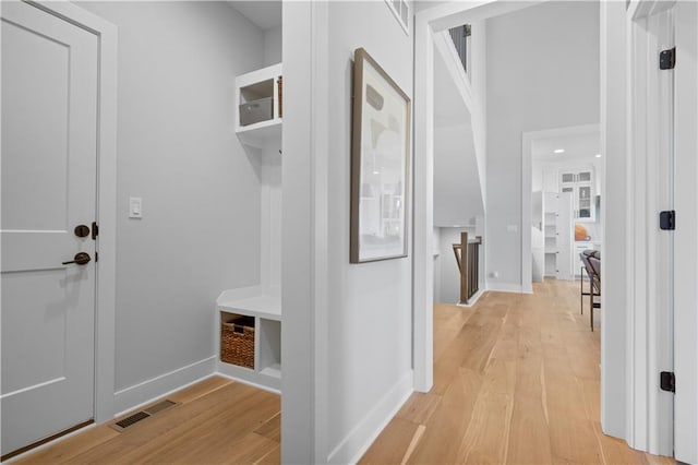 mudroom featuring baseboards, visible vents, and light wood finished floors