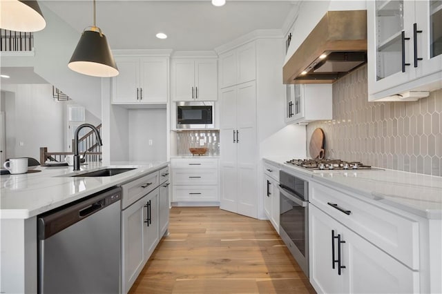 kitchen featuring a sink, white cabinetry, light wood-style floors, appliances with stainless steel finishes, and ventilation hood