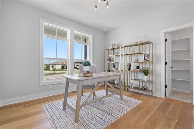 home office with light wood finished floors, an inviting chandelier, and baseboards