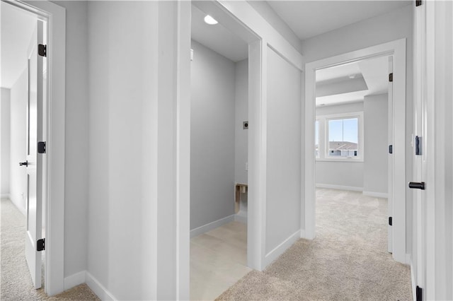 hall featuring light carpet and baseboards