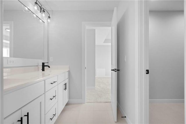 bathroom with tile patterned floors, a sink, baseboards, and double vanity