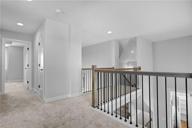 hall featuring recessed lighting, baseboards, carpet flooring, and an upstairs landing