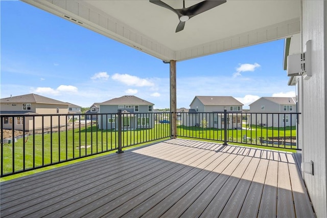 deck featuring a residential view, a ceiling fan, and a lawn