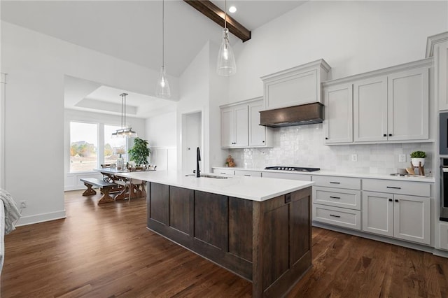 kitchen featuring an island with sink, black gas stovetop, sink, backsplash, and pendant lighting