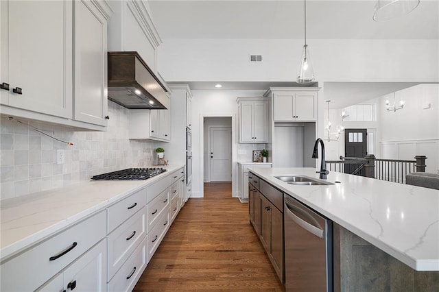 kitchen with appliances with stainless steel finishes, custom range hood, white cabinets, decorative light fixtures, and sink