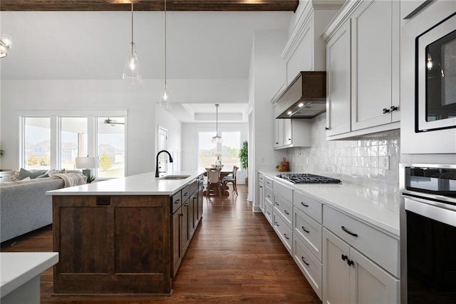 kitchen with an island with sink, stainless steel appliances, dark hardwood / wood-style flooring, sink, and decorative backsplash