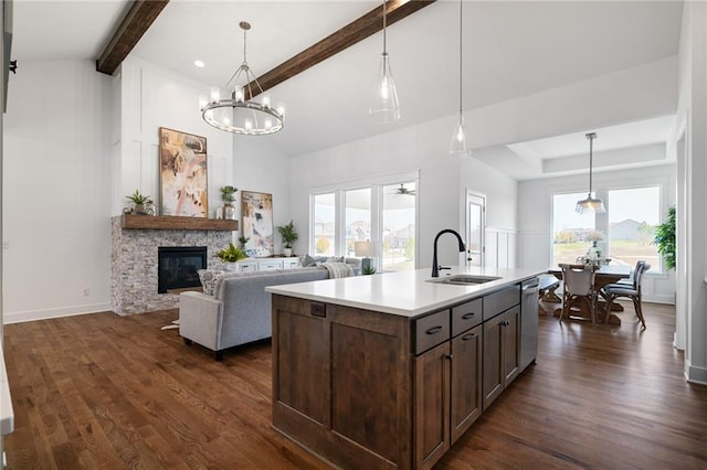 kitchen with an island with sink, a fireplace, decorative light fixtures, sink, and stainless steel dishwasher