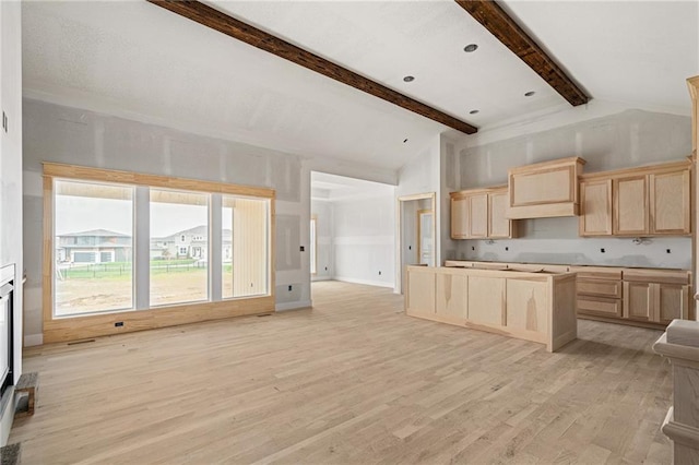 kitchen with light brown cabinetry, a center island, light wood finished floors, open floor plan, and vaulted ceiling with beams