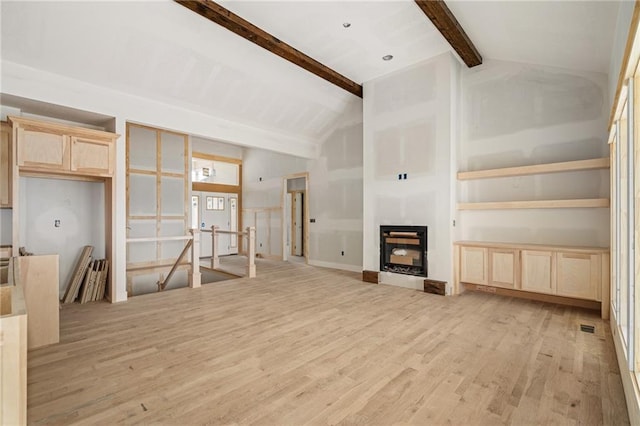 unfurnished living room with vaulted ceiling with beams, light wood-style floors, and a fireplace