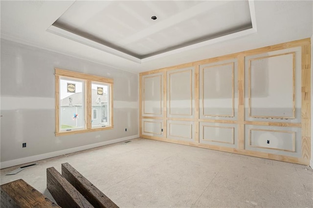 empty room featuring baseboards and a raised ceiling