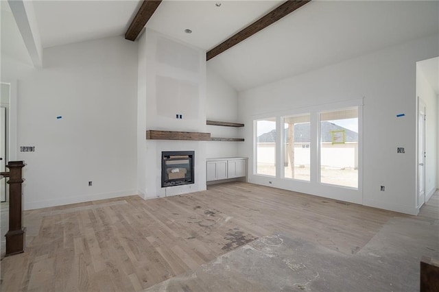 9346 Gander St, Lenexa, KS 66227 - unfurnished living room featuring high vaulted ceiling, beam ceiling, a glass covered fireplace, and light wood finished floors