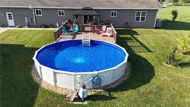 outdoor pool with a gazebo, a yard, cooling unit, and a wooden deck