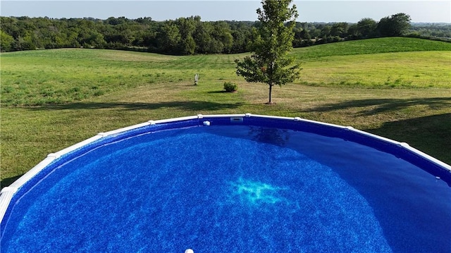 view of swimming pool with a yard and a rural view