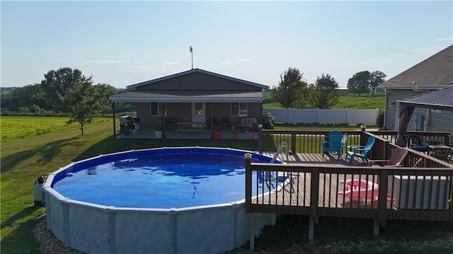 outdoor pool featuring fence, a deck, and a yard