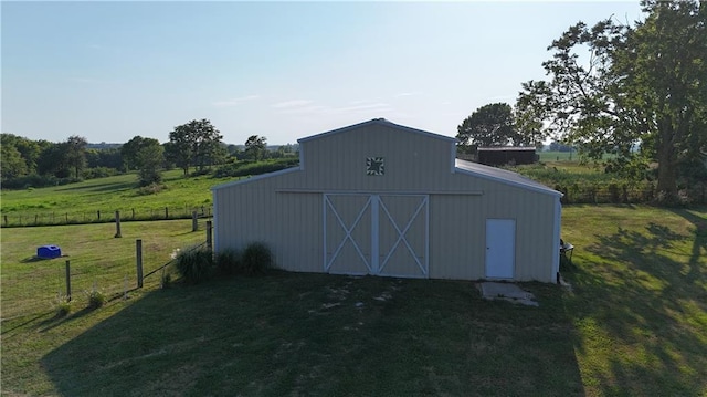 view of barn featuring a yard, a rural view, and fence