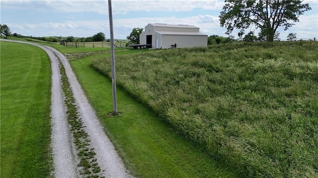 view of yard featuring driveway, an outdoor structure, and a rural view