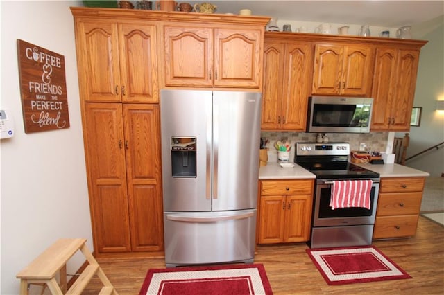 kitchen with stainless steel appliances, light countertops, and light wood-style floors