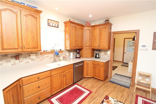 kitchen featuring a sink, light wood-style floors, light countertops, stainless steel dishwasher, and tasteful backsplash