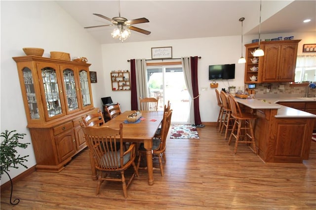 dining room featuring vaulted ceiling, light wood-type flooring, and baseboards