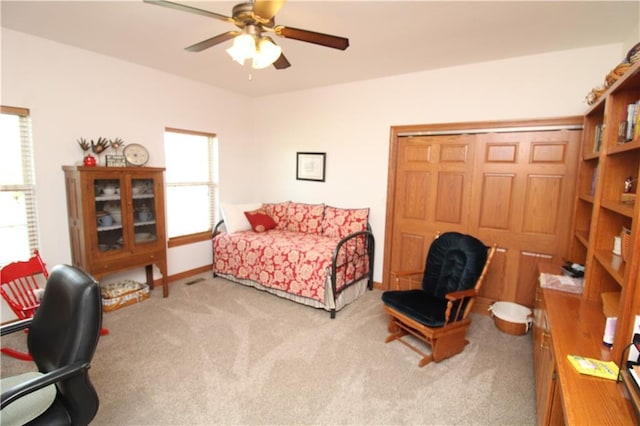 bedroom featuring a closet, light carpet, ceiling fan, and baseboards