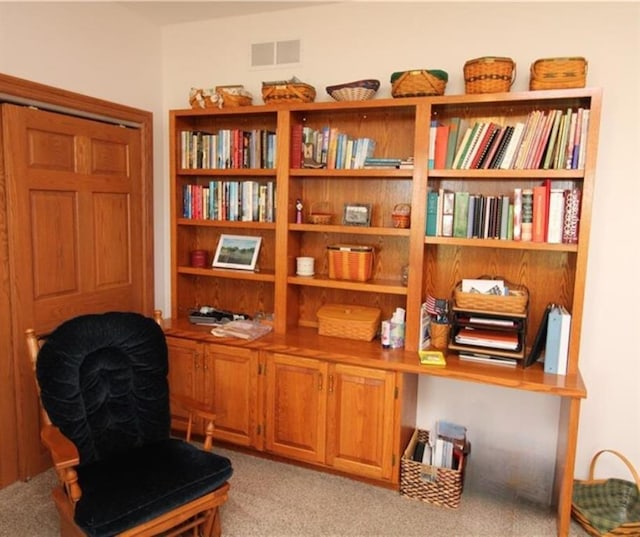 sitting room featuring light carpet, visible vents, and built in desk