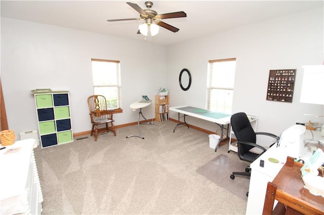 home office with light carpet, a ceiling fan, and baseboards