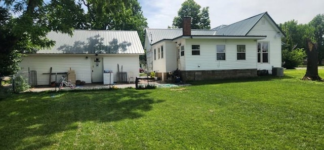 rear view of property featuring central AC unit and a lawn