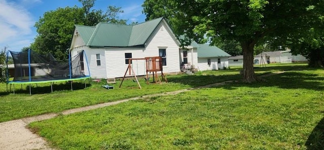 back of house featuring a trampoline and a yard